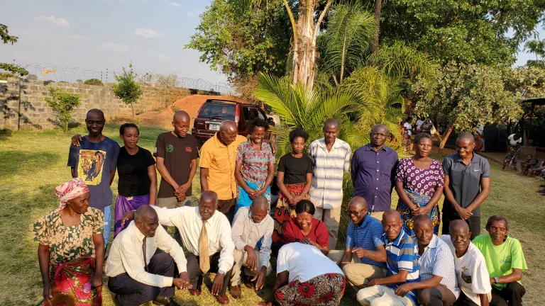 a group of people outside in the shade of a tree