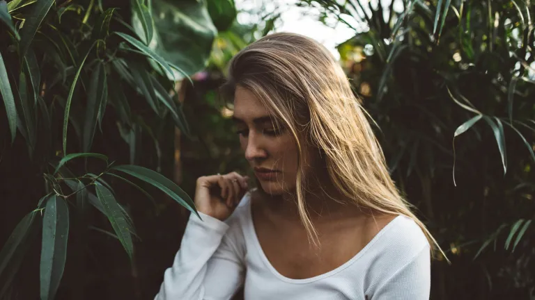 a sad woman surrounded by greenery