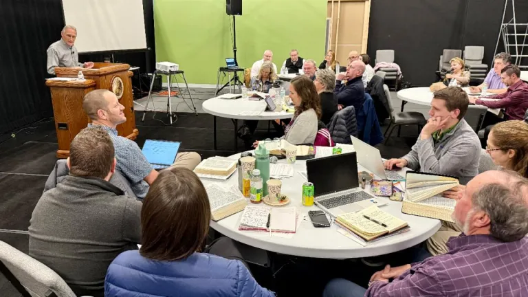 people seated around tables listening to a presenter