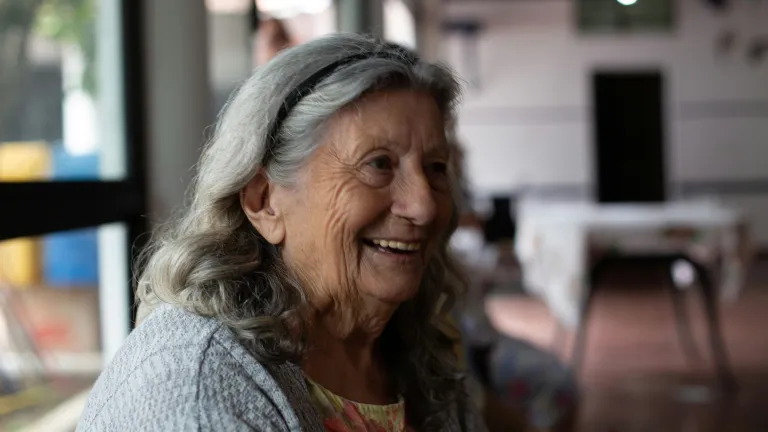 a smiling woman with gray hair sitting indoors