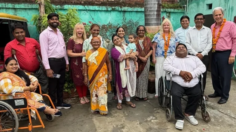 a group of people seated and standing outside an old green building