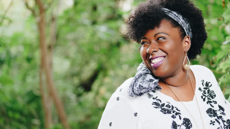 a smiling woman with trees in the background