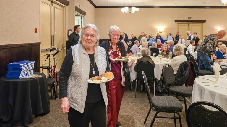 women with plates of food in a banquet room