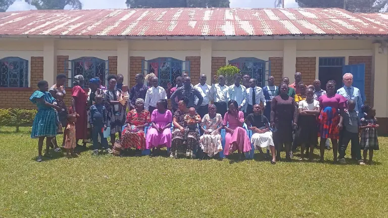 a large group of people gathered on a green lawn in front of a building