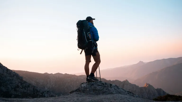 a man outside hiking with rolling hills off in the distance