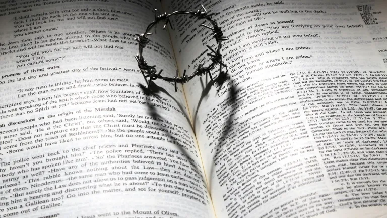 a crown of thorns casting a heart-shaped shadow on a Bible opened to a passage about Christ