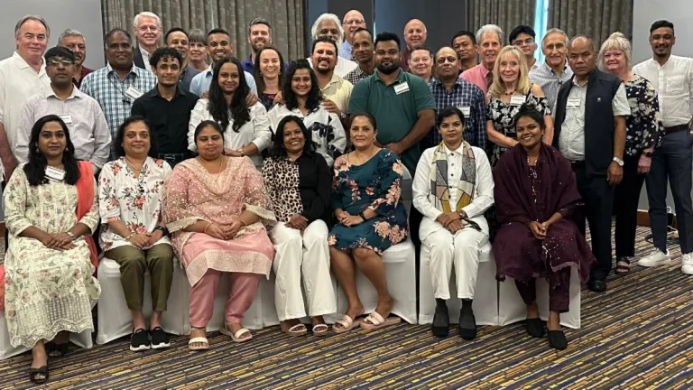 a large group of people sitting and standing indoors