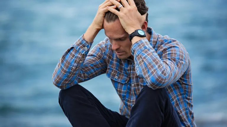 a man sitting and holding his head in his hands