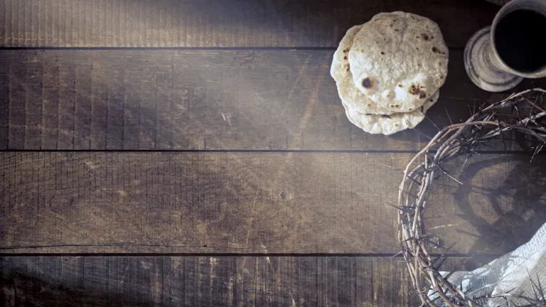 The Passover service commemorates the death of Jesus Christ. a crown of thorns, unleavened bread, and wine on a wood surface