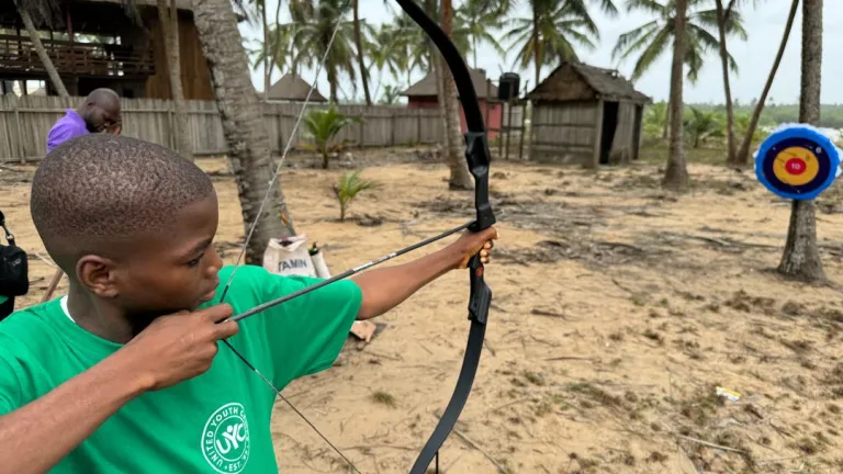 a boy aiming a bow and arrow at a target