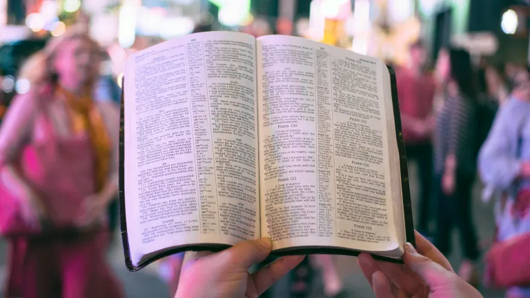 Person holding a Bible with busy city in the background