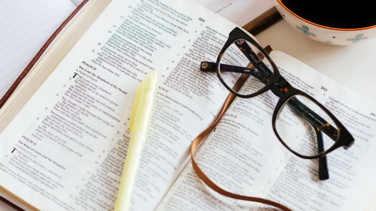 bible studying layout with bible, pens, glasses and a cup of coffee