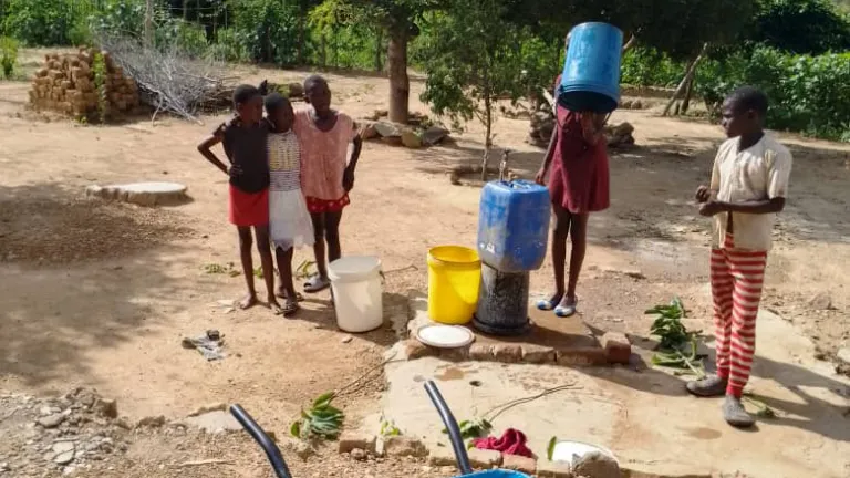 Children getting water from the well a group of children standing outside with some buckets