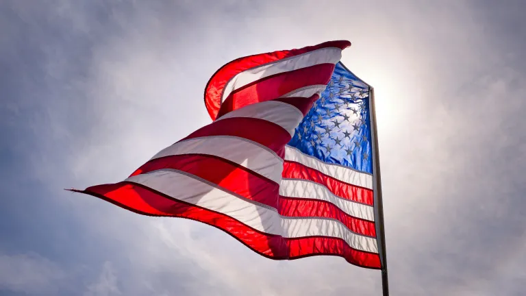 Looking up toward the sky with an American flag flying in the wind.