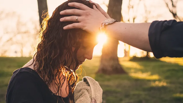 A minister laying hands on a women's head and praying after water baptism.