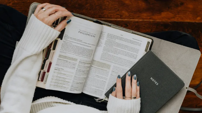 A woman reading a Bible with a notebook.