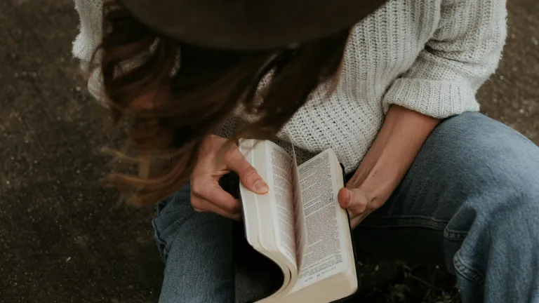 A woman opening a Bible.