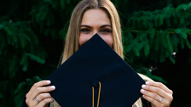 a woman holding up a graduation hat