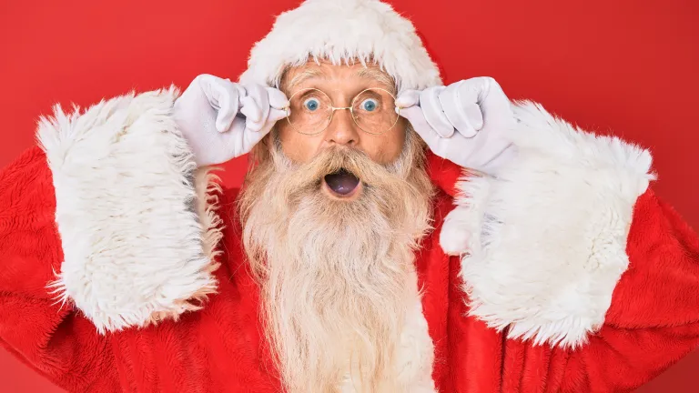 Santa Claus looking surprised against a red background