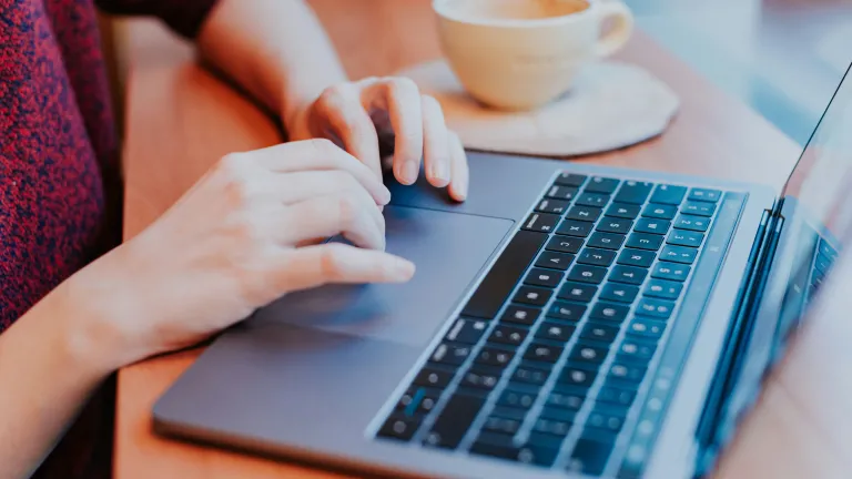 A woman typing and scrolling on a laptop.