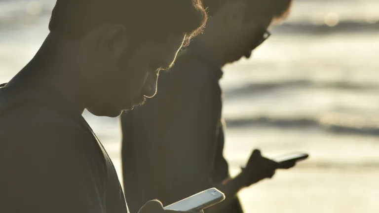 Two guys staring at the mobile phones.