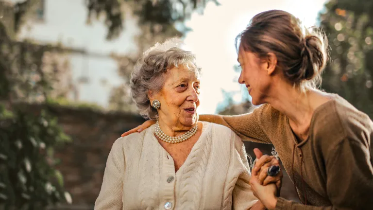 joyful adult daughter greeting happy surprised woman in garden