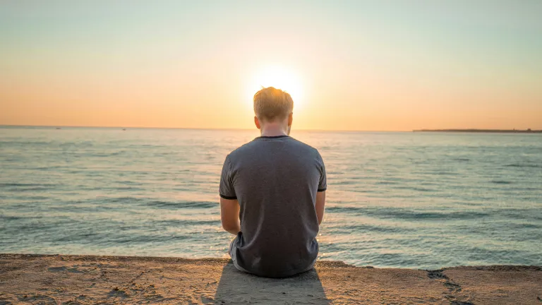 When life doesn’t go as planned and the weight feels heavy, remember—even with one string, you can still play a beautiful melody. God can work through brokenness to create something meaningful if we keep following Him. A man sitting on the beach with his head down.