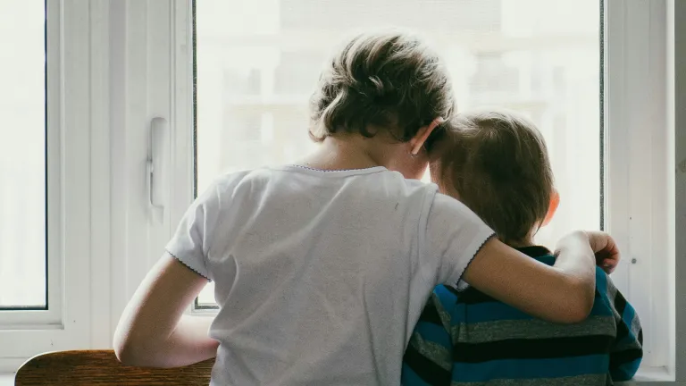 A older sister hugging her little brother.