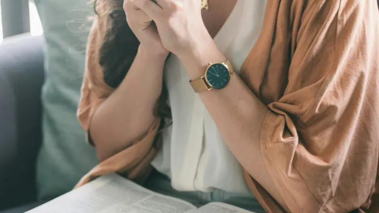We should be continually thanking and praising God for His countless blessings and benefits! A woman with a Bible in her lap with clasped hands praying.