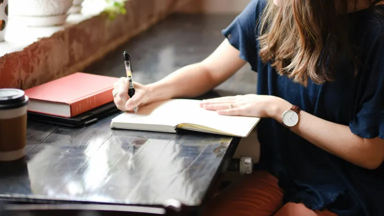 Writing simple statements about our emotions and talking to God about them in prayer is one way to process them. a woman writing in a notebook at a table