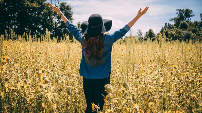 a woman in a field with her arms spread wide above her