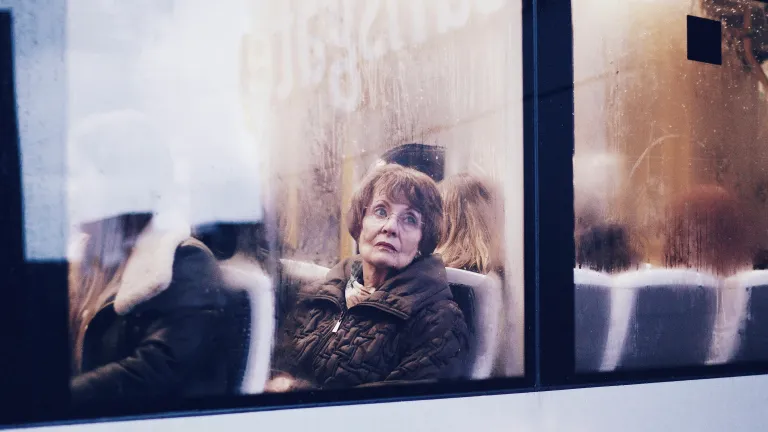 A woman sitting in a bus looking out the window.