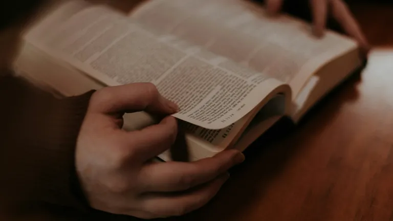 A person holding an open Bible.