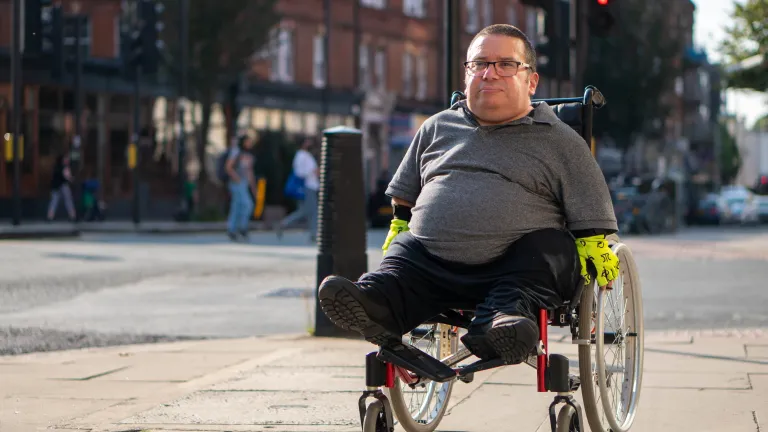 everyone who has a disability can accomplish as much as anyone else -- and just maybe more than he otherwise would -- and, if he allows that physical disability to motivate instead of discourage him. A man in a wheelchair going down a city street sidewalk.