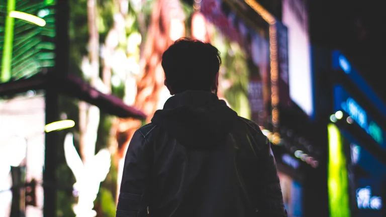 Character is a distinctive trait, a pattern of behavior that shows moral strength, self-discipline and fortitude. A man walking in a big city with lit billboards.