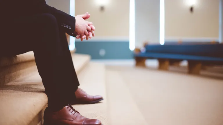 a man wearing a suit sitting on indoor steps