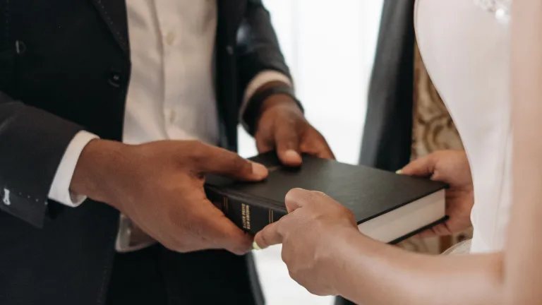 a bride and a groom holding a Bible together