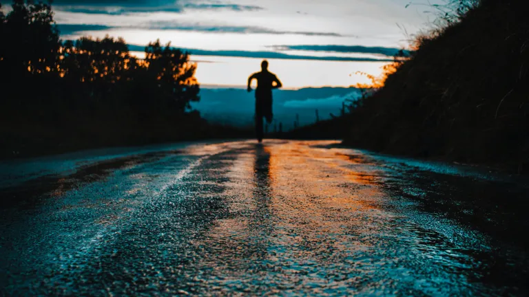 Silhouette photo of a person running on road.