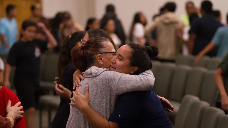 Forgiveness is something that we all need from each other. two women hugging in the midst of a room full of people
