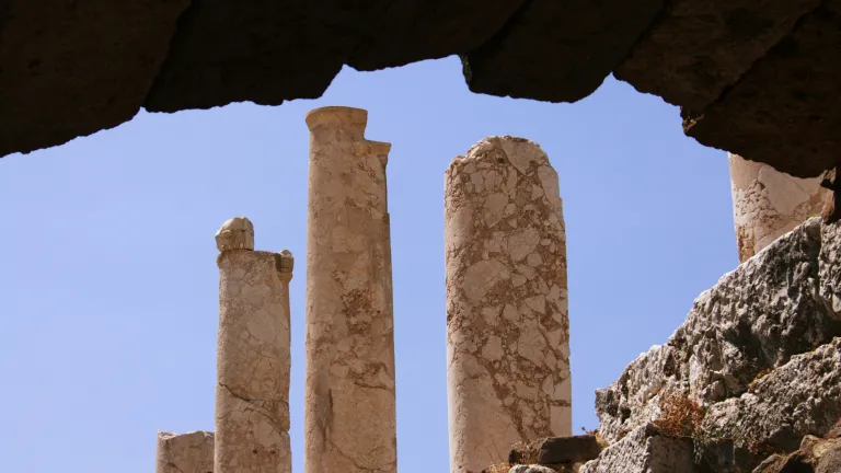 a group of stone pillars against a blue sky with a dark archway in the foreground