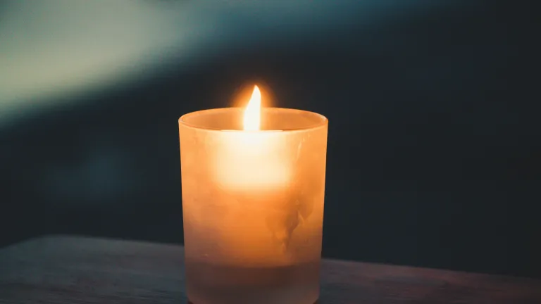 a yellow candle on a wooden table