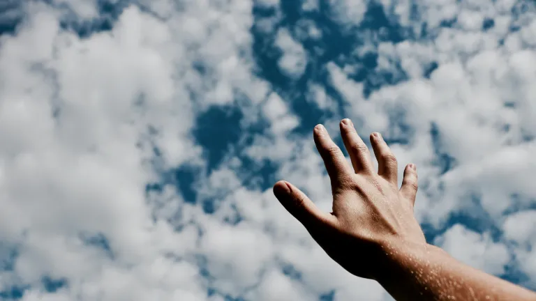 Angels are real, but one must be cautious about giving the credit to angels when the real credit for miracles and answered prayers should go to God! a hand reaching towards a cloudy sky