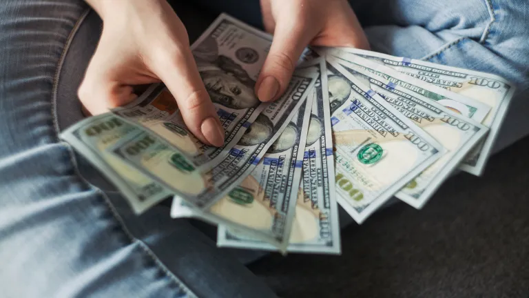 a sheaf of 100-dollar bills held in a woman's hands