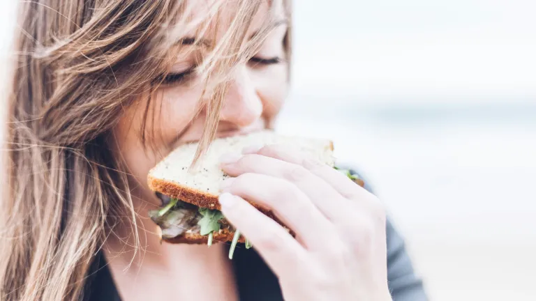 A young woman eating a healthy looking sandwich,