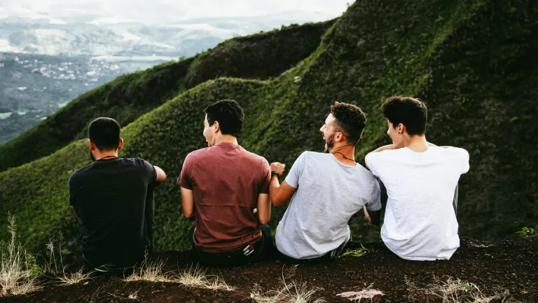 Four young men sitting outdoors in the mountains