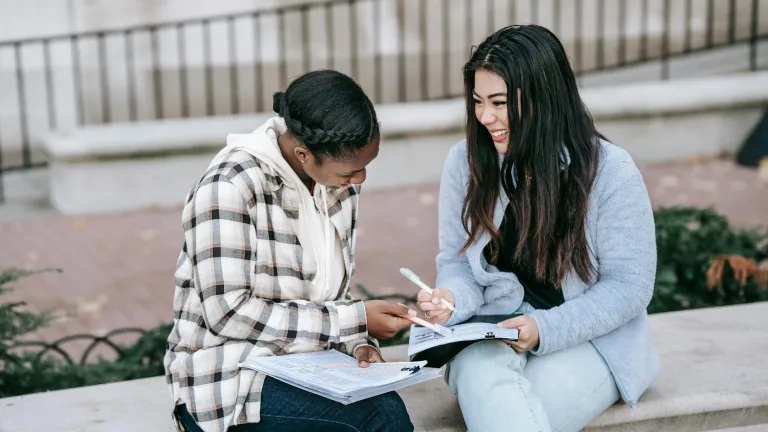 What responsibilities come with friendship? Two young women sitting outside on a bench and writing in notebooks