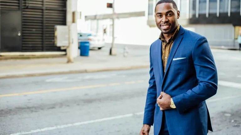 a man wearing a business suit walking in a city road