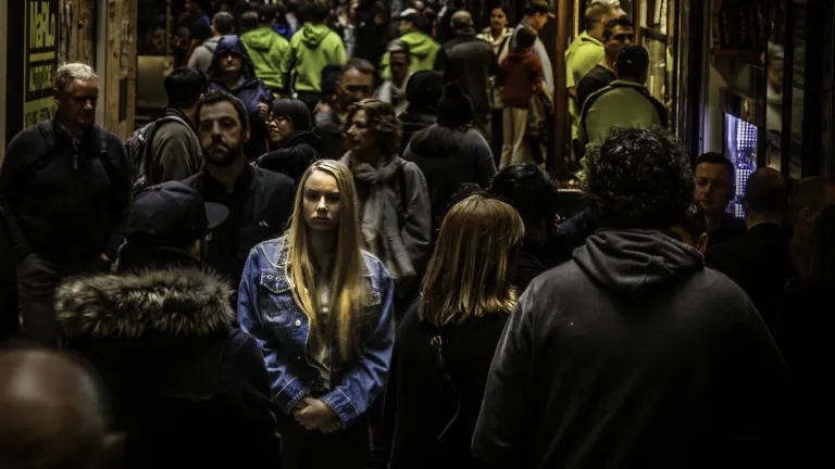 A woman walking in a crowded alley with numerous people.