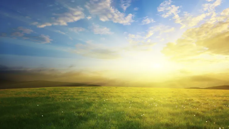 Sunrise of over a green grass hill