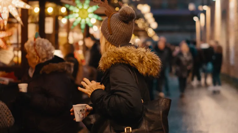 Those of us who do not celebrate Christmas, knowing how to respond to someone who might be sincerely wishing us well is difficult. A woman standing in line surrounded by people and Christmas lights.